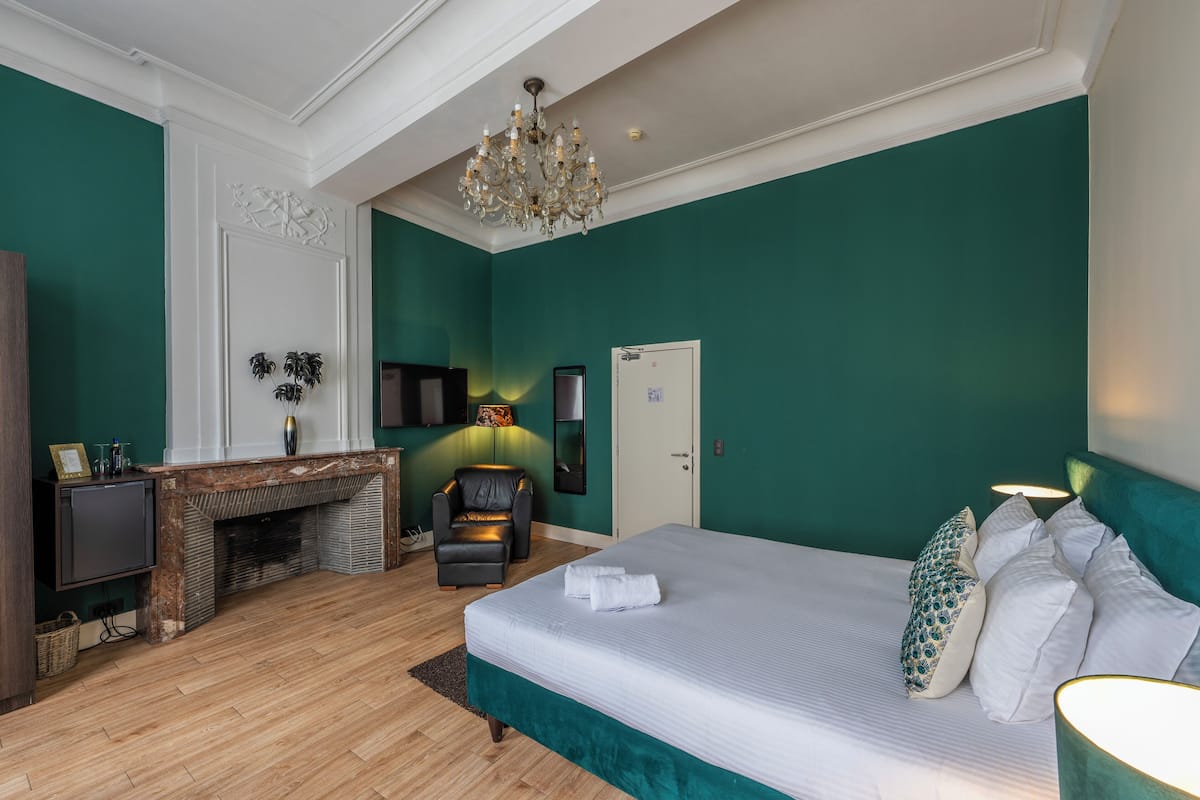 Un dormitorio con una cama grande, chimenea, televisor y candelabro.