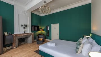 Un dormitorio con una cama grande, chimenea, televisor y candelabro.