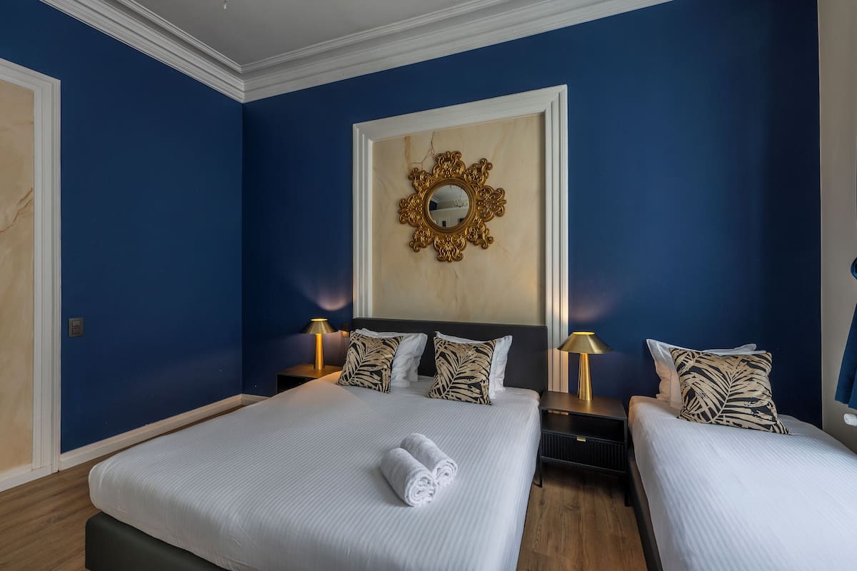 Habitación de hotel con dos camas, un espejo grande y piso de madera.