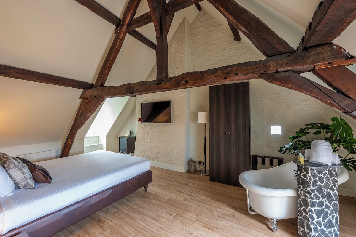 Un dormitorio con cama, bañera y un pedestal de piedra.