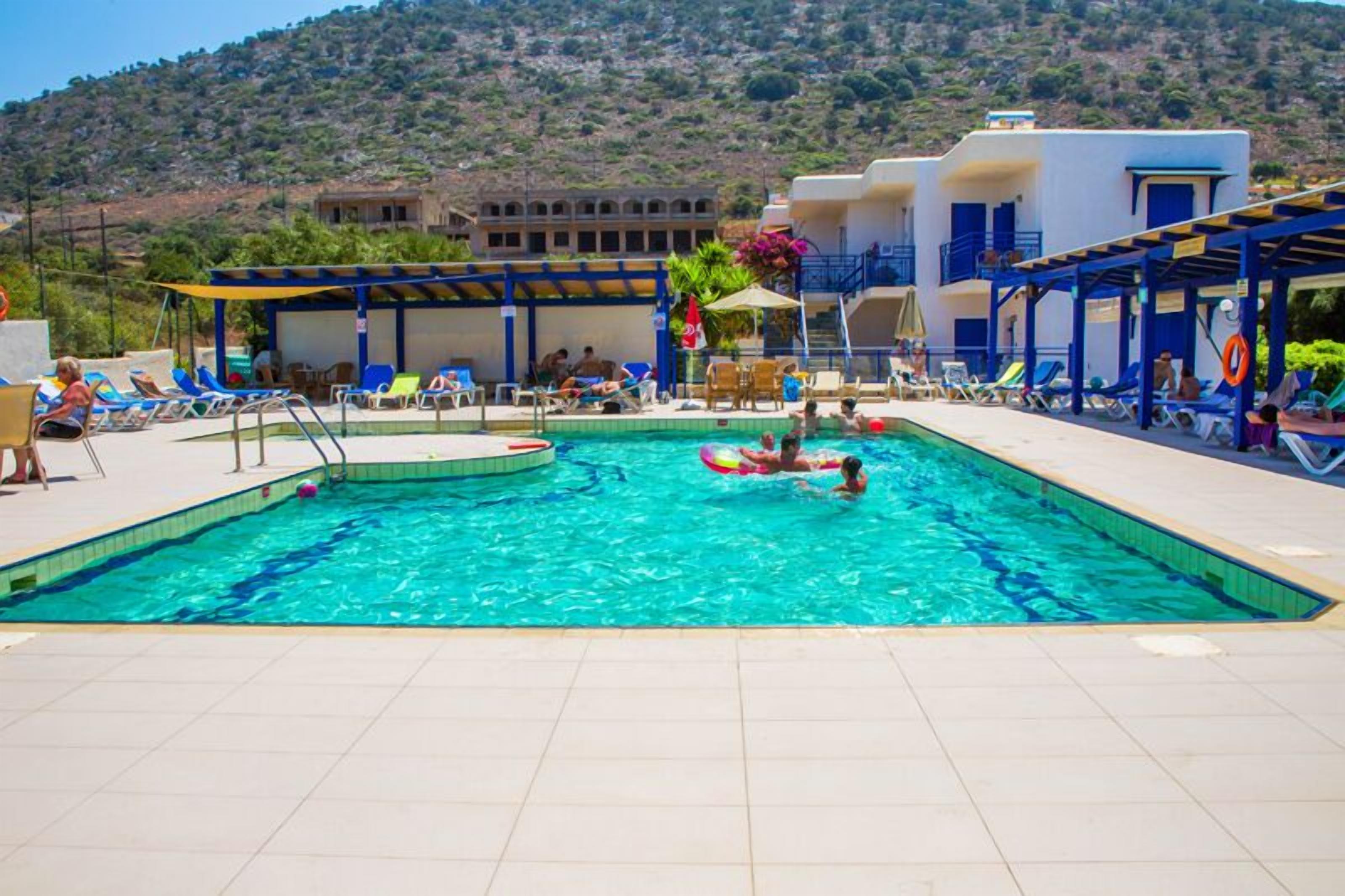 Una piscina al aire libre, sombrillas, sillones reclinables de piscina