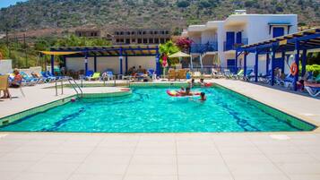Una piscina al aire libre, sombrillas, sillones reclinables de piscina