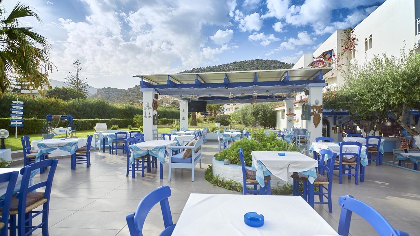 An outdoor patio area with tables and chairs, a pergola, and a view of a mountainous landscape.