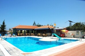 Ein Swimmingpool mit Liegestühlen und einer überdachten Sitzgelegenheit.