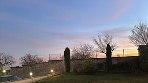 An outdoor seating area with a stone fire pit, surrounded by grass and trees. - La Bonbonniere, Sure Hotel Collection by Best Western (Talant)