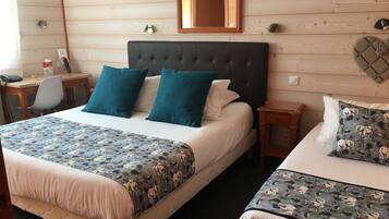 A hotel room with a large bed, a smaller bed, a desk, and a mirror on the wall.