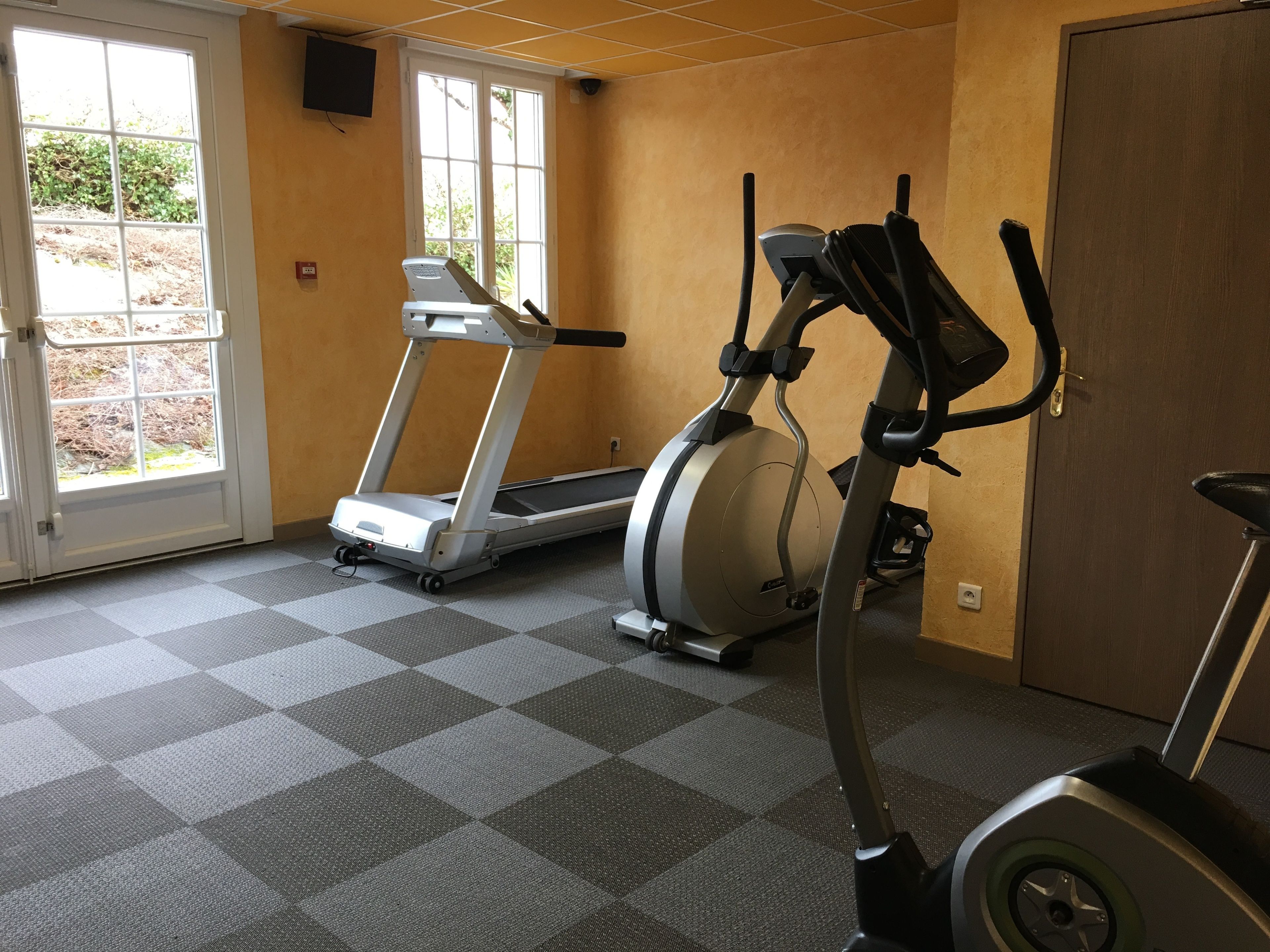 Et fitnessrum med løbebånd, crosstrainer og motionscykel.