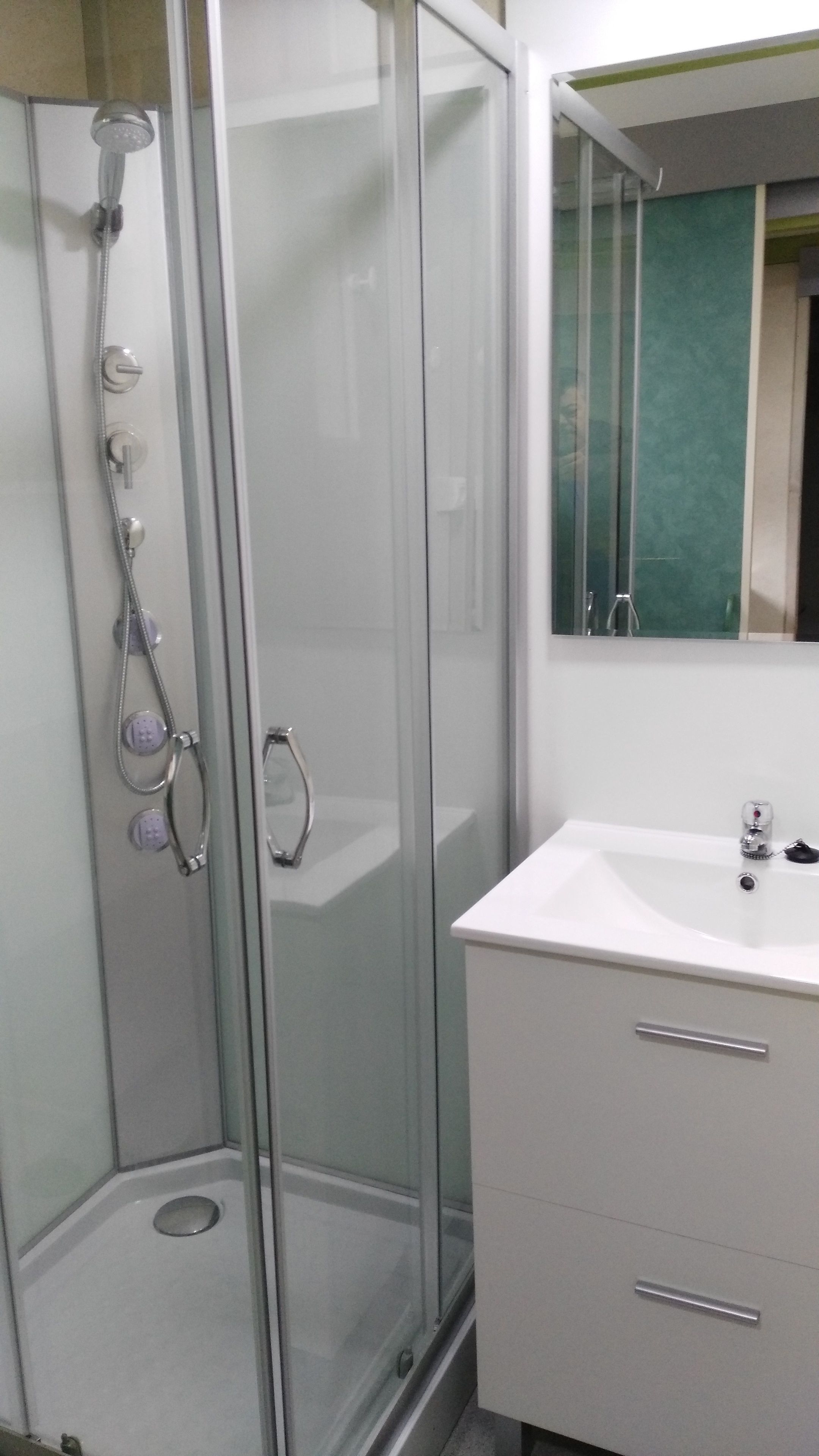 A bathroom with a glass-enclosed shower, a white sink, and a mirror above the sink.
