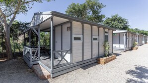 Una hilera de casas móviles de un piso, con un porche cubierto y un pequeño jardín.