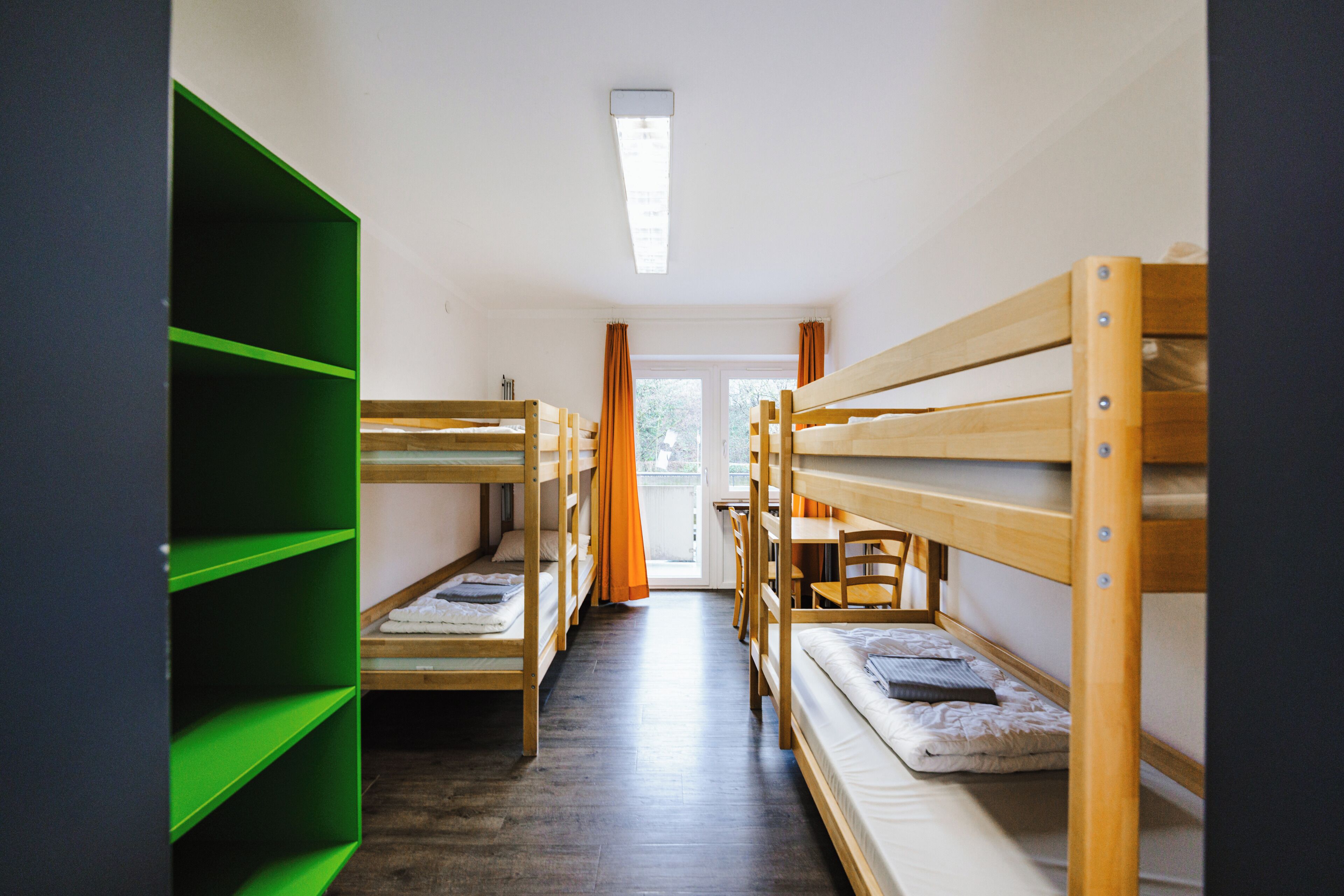 Un dormitorio con literas, un escritorio y una estantería verde.