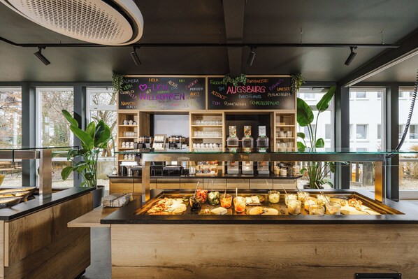 A buffet area with various food items and a chalkboard menu in a modern restaurant setting.