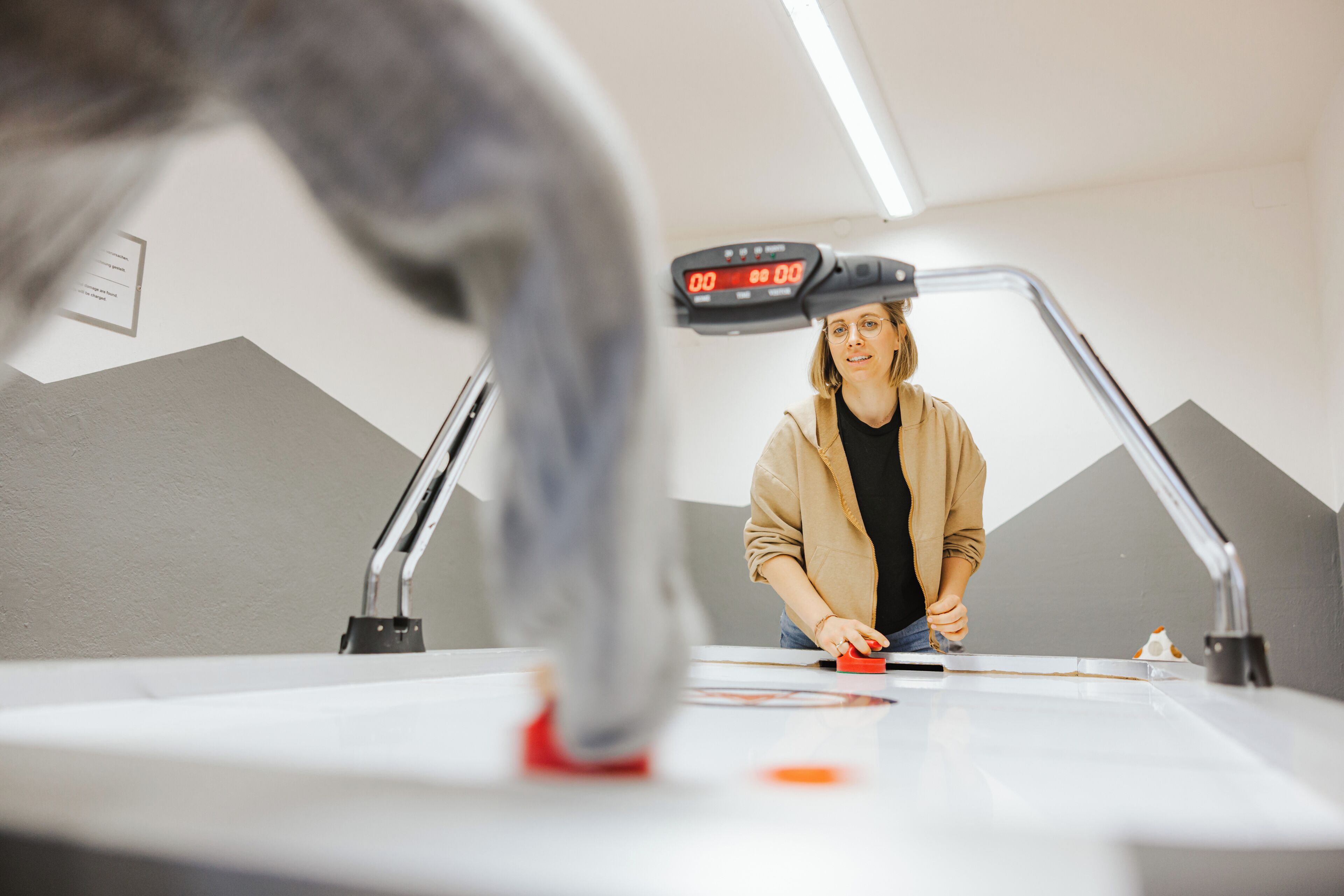 Iemand staat bij een bureau met een digitale timer, een bureaulamp en een klein beeldje.