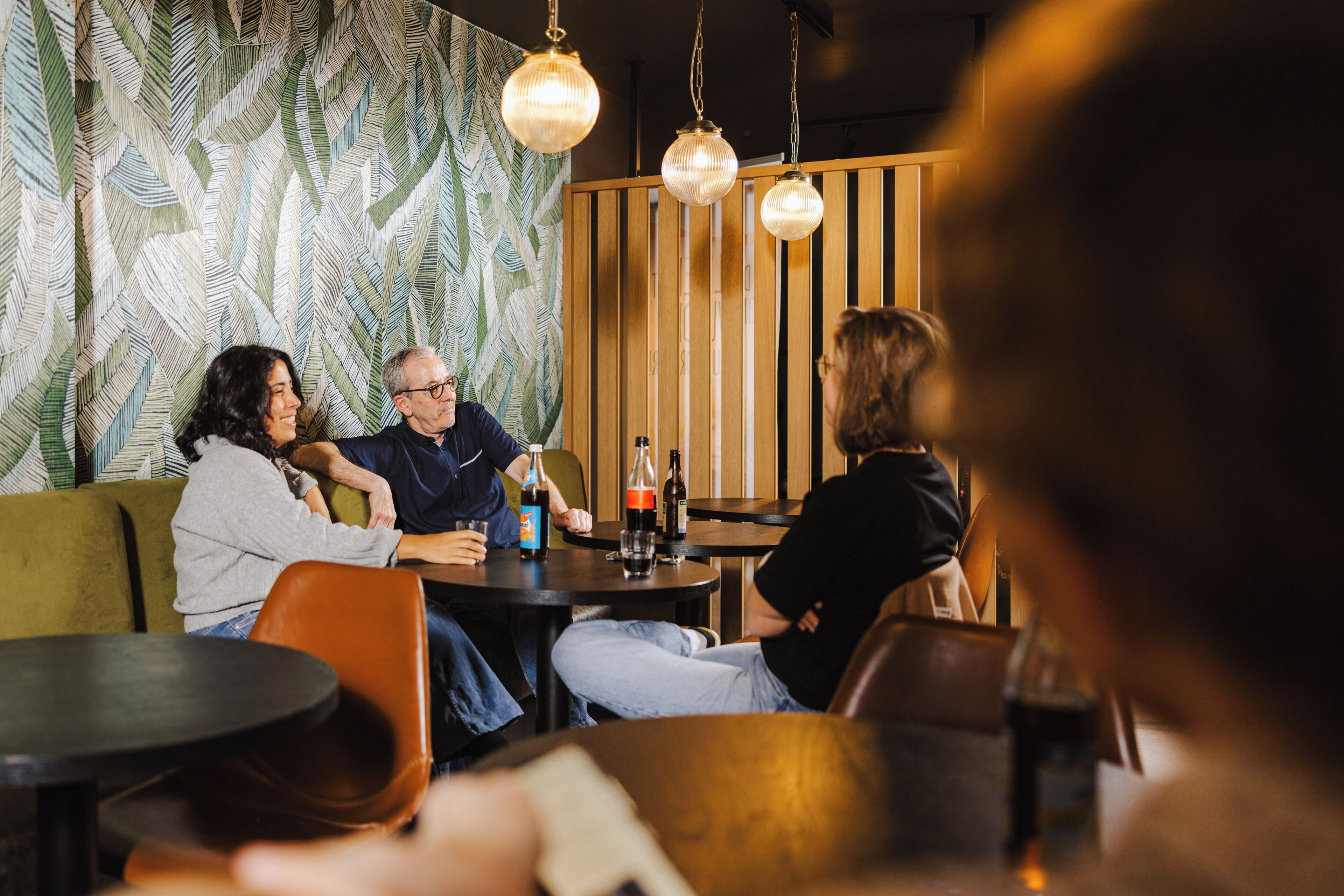 Ein Restaurantinnenraum mit Holzvertäfelung, hängenden Pendelleuchten und einer Wand mit Muster.