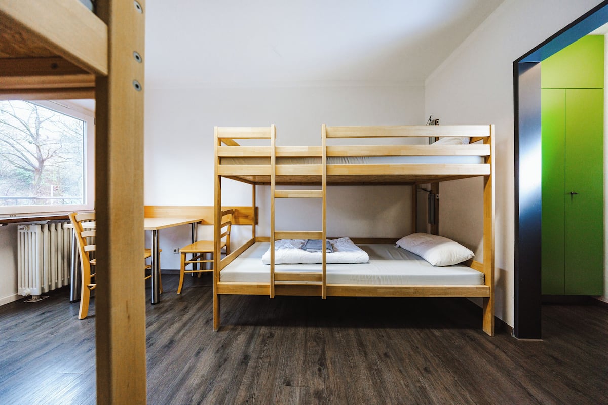 A bunk bed with a desk and chair, a radiator, and a green door.