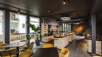 A modern cafe with yellow chairs, a wooden counter, and large windows.