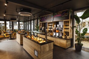 Un café moderno con mobiliario de madera, una barra central con comida y estantes con artículos.
