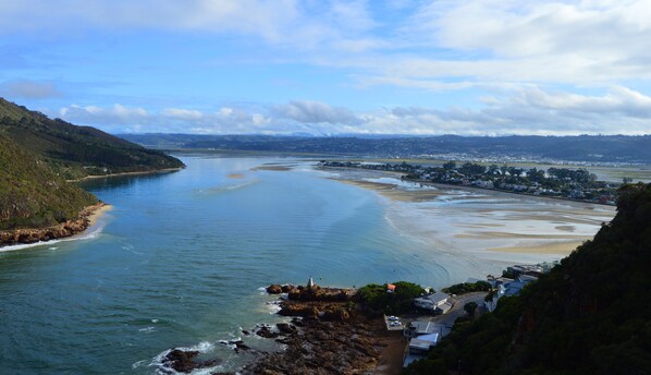 A coastal town with a beach, rocky shoreline, and a view of the sea. - Double Dutch B & B (Knysna)