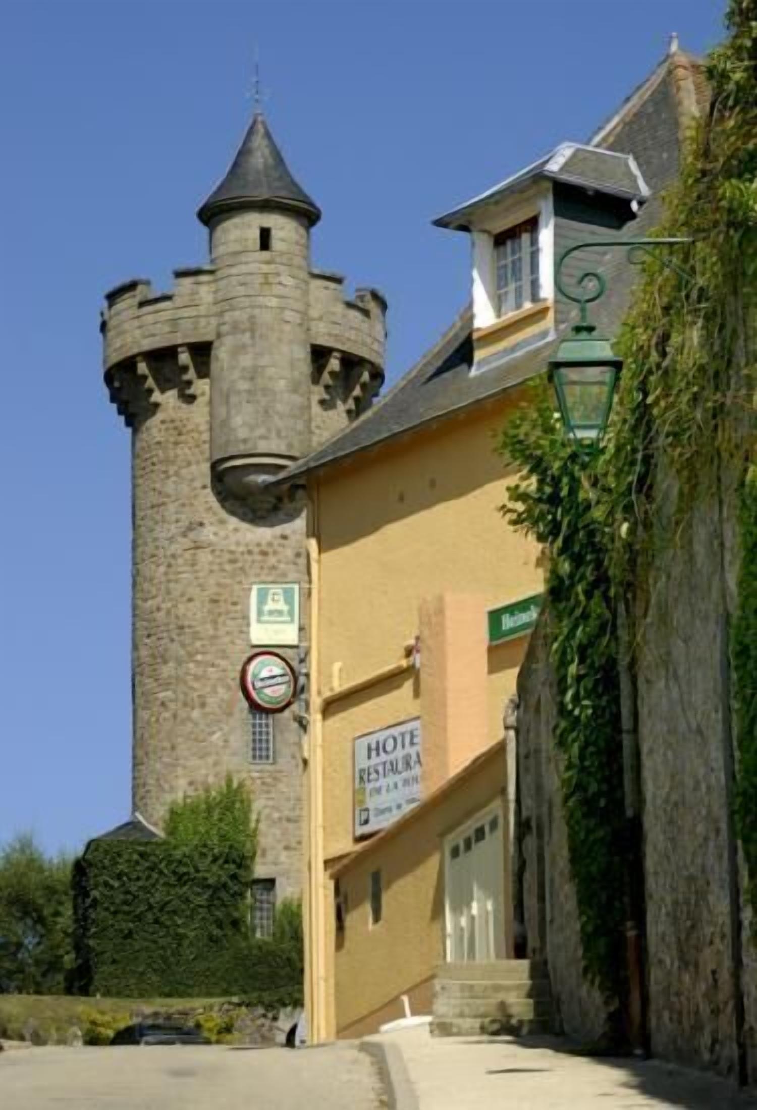 A historic stone tower attached to a building with a sign for a hotel.