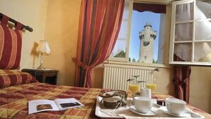 A hotel room with a bed, a tray with breakfast items, a window with a view of a tower, and curtains. - Hôtel-Restaurant de la Tour (Masseret)