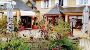 A courtyard with a restaurant named "Entree D'Art" and a small outdoor seating area. - Hôtel-Restaurant de la Tour (Masseret)
