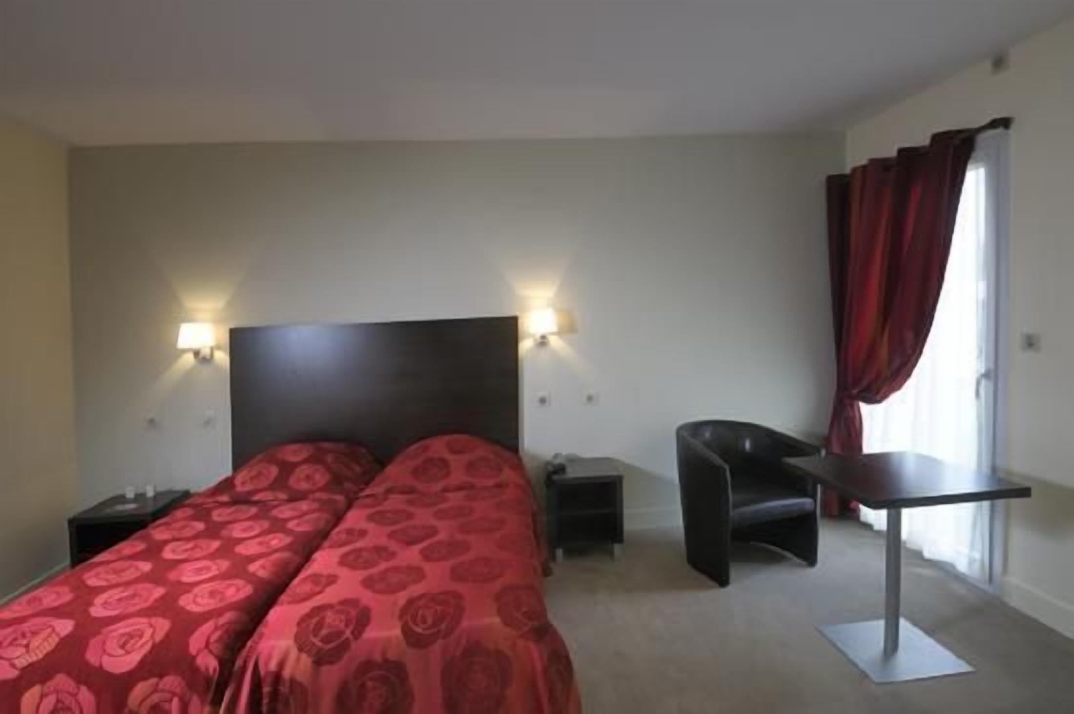 A hotel room with a bed, bedside tables, a desk, and a chair.