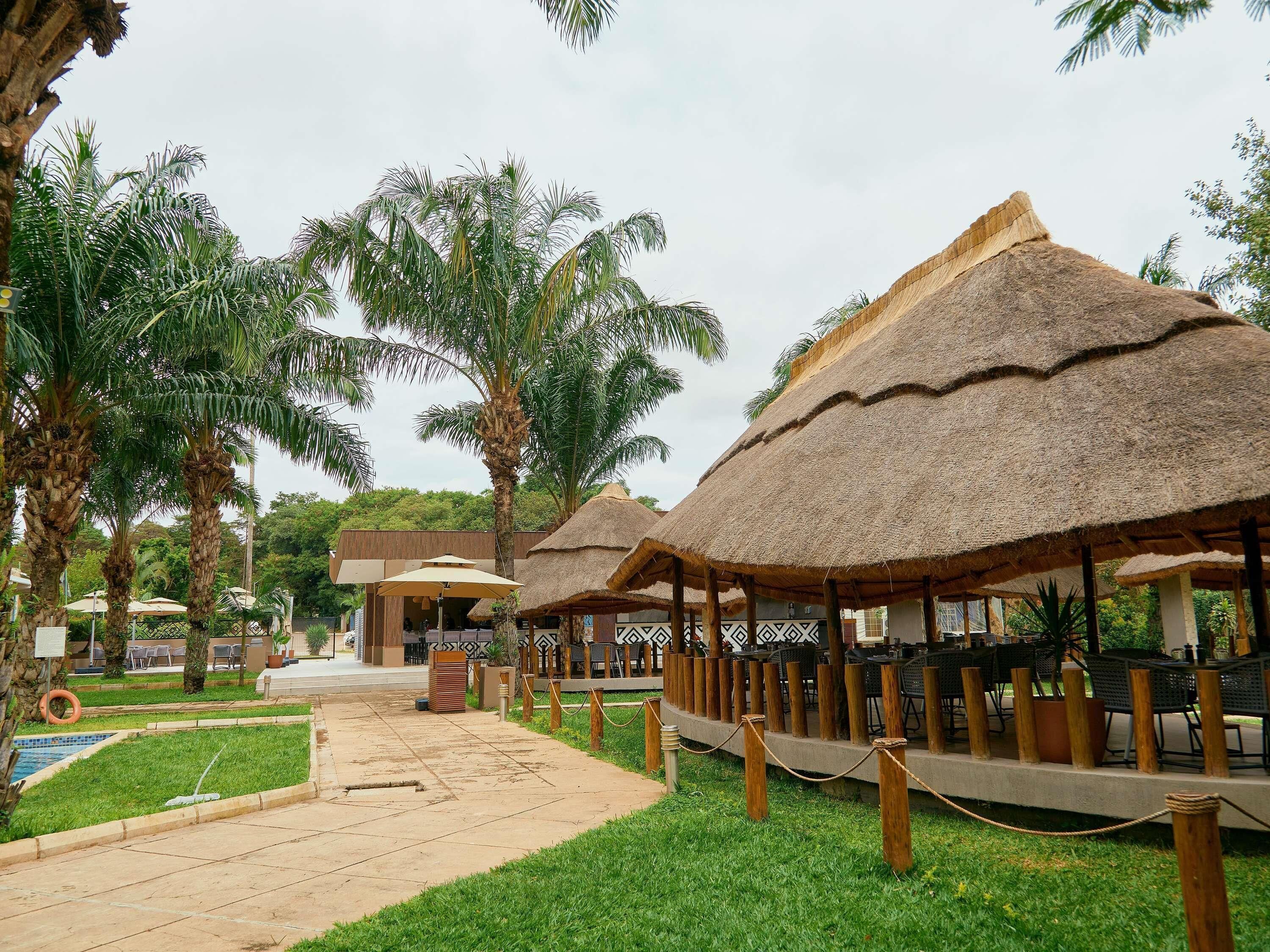 Ein Resort mit strohgedeckten Gebäuden, einem Pool und einem gepflasterten Weg.