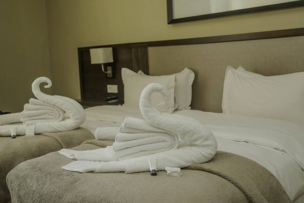 A hotel room with a neatly made bed, a nightstand with a lamp, and a framed picture on the wall.