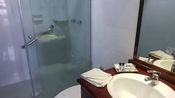 A bathroom with a glass shower enclosure, a white sink with a mirror, and a toilet.