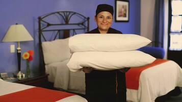 A hotel room with a bed, a nightstand, a lamp, and a picture on the wall.