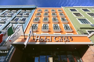A hotel with a prominent orange facade, multiple balconies, and flags.