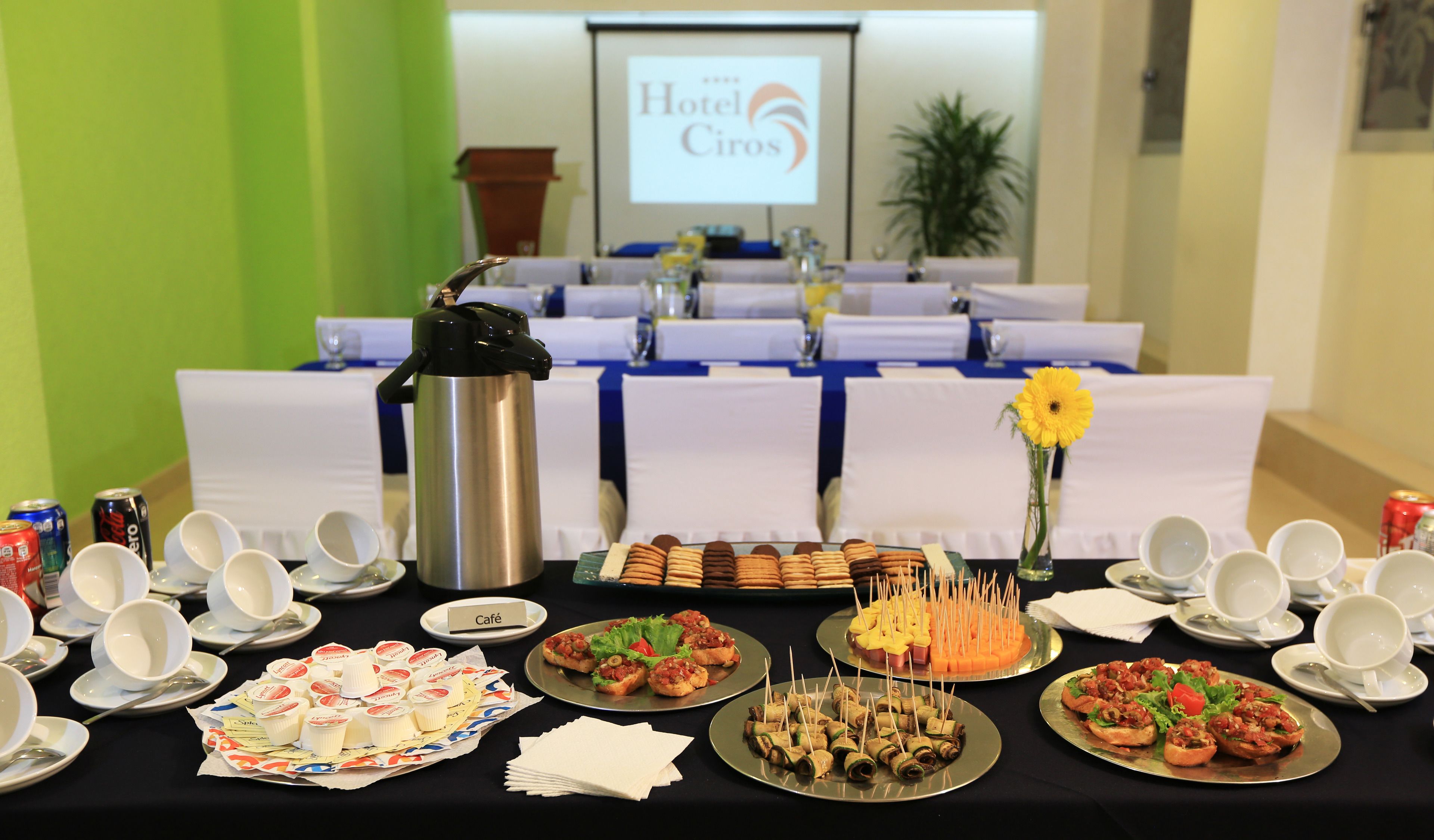 A buffet table with various food items, a coffee pot, and a 'Café' sign.