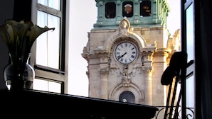 Une vue sur un bâtiment historique doté d’une tour horloge, prise à travers une fenêtre.