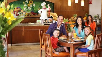 Enjoy a family meal in a cozy dining area with a vibrant mural and comfortable seating.