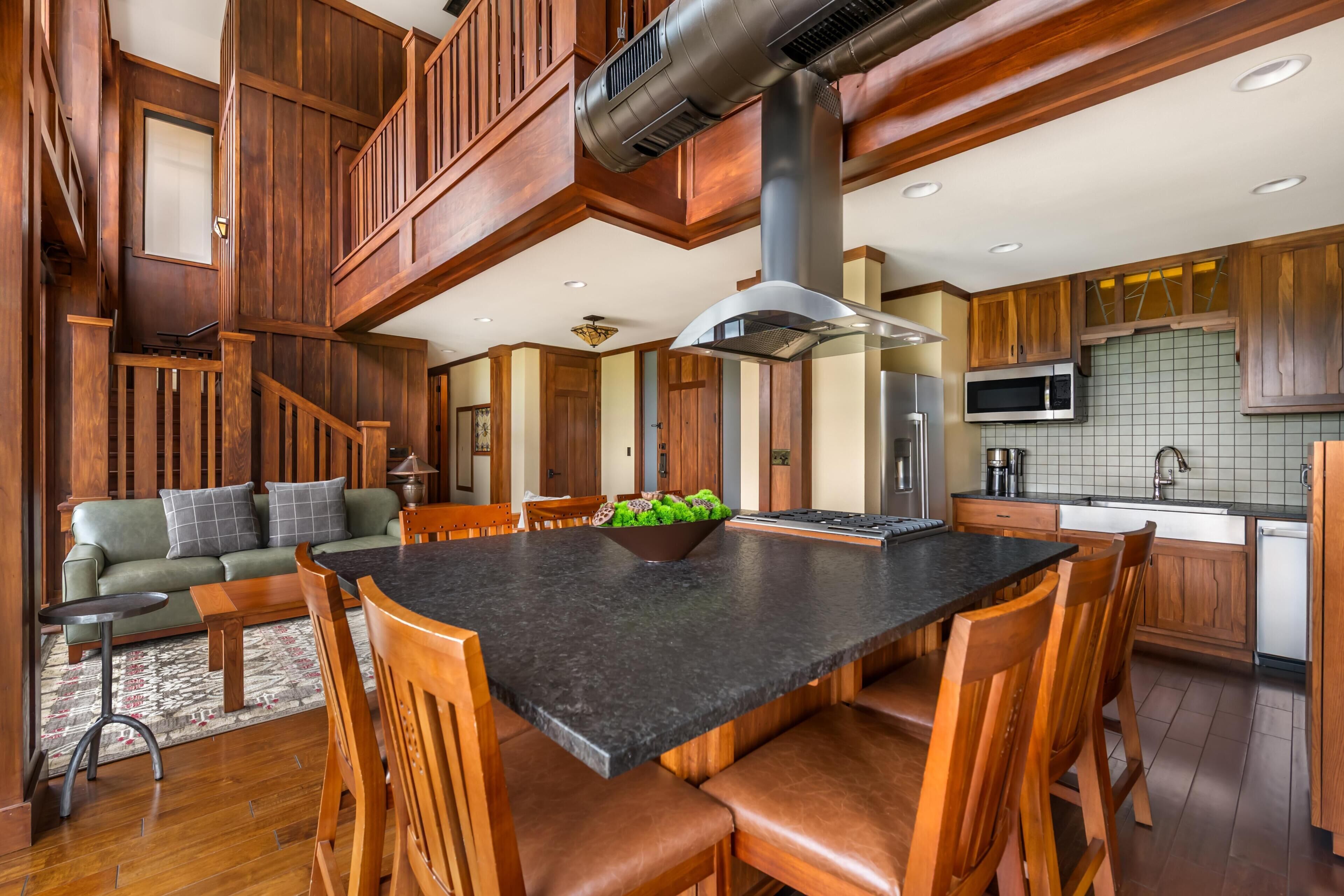 A spacious kitchen with a large island, wooden cabinetry, and a built-in microwave.