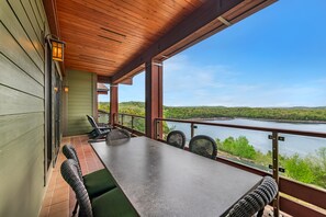 A covered patio with a table and chairs, overlooking a lake and greenery. - Hilton Grand Vacations Club Long Creek Ridgedale (Ridgedale)