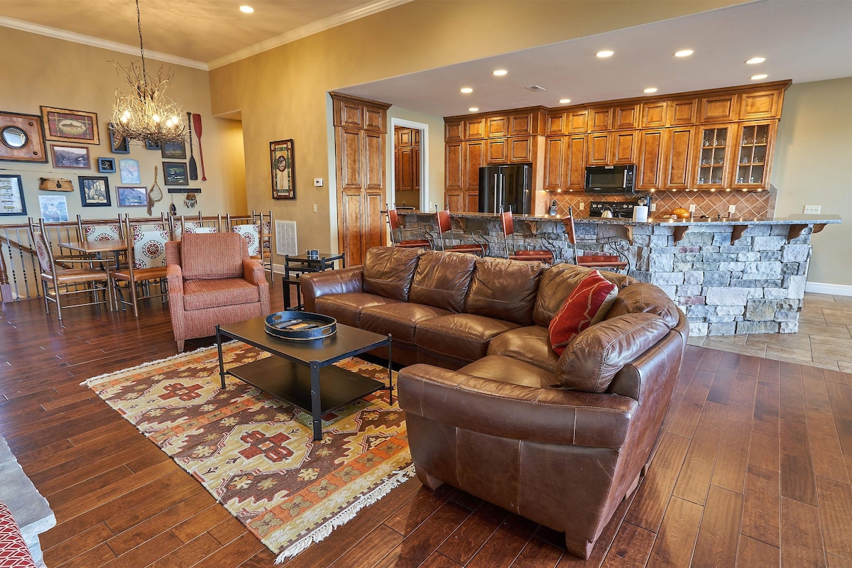 A spacious living room with a leather sofa, a coffee table, and a patterned rug.