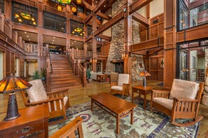 A spacious lobby with a grand staircase, wooden furniture, and a stone fireplace. - Hilton Grand Vacations Club Long Creek Ridgedale (Ridgedale)