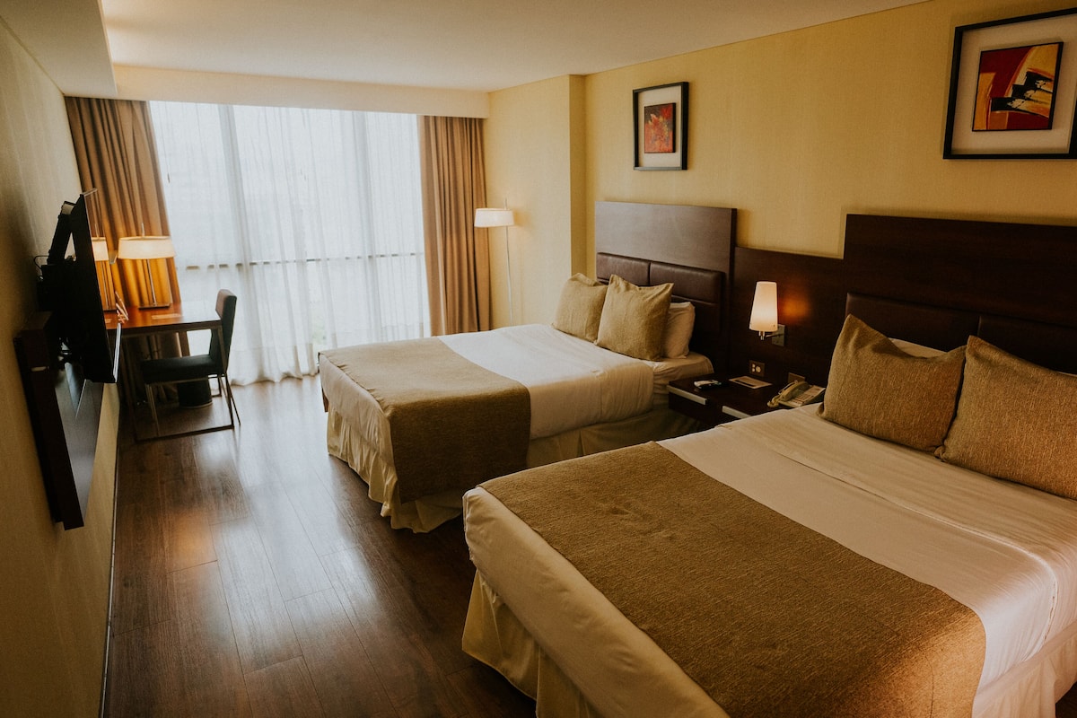 Habitación de hotel con dos camas, un escritorio y una silla.