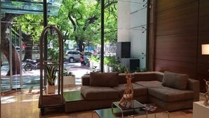 A modern lobby with a brown sofa, a glass partition, and a view of the street outside.
