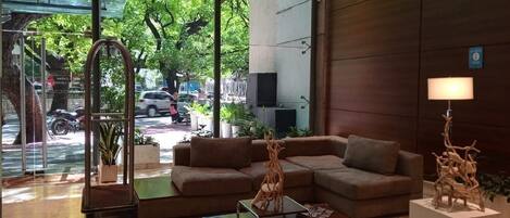 A modern lobby with a brown sofa, a glass partition, and a view of the street outside.