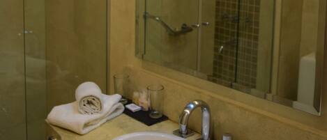 Un baño con cabina de ducha de vidrio, un lavabo con espejo y un perchero para toallas.