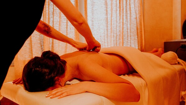 A massage therapy session in a room with a bed and a curtain in the background.