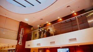 A modern hotel interior with a glass railing, a visible brand sign, and a digital screen displaying water usage information.