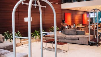 A modern lobby with a luggage cart, seating area, and a large window.