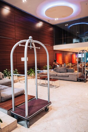 A modern lobby with a luggage cart, seating area, and a large window. - Howard Johnson by Wyndham Córdoba La Cañada (Córdoba)