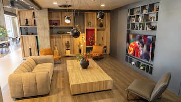 Una sala de estar moderna con un sofá, una mesa de centro y un televisor. Hay estanterías con adornos y una planta.