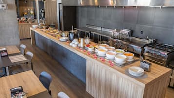 Un área de cocina moderna con mesas de buffet, varios recipientes de comida y una máquina de café.