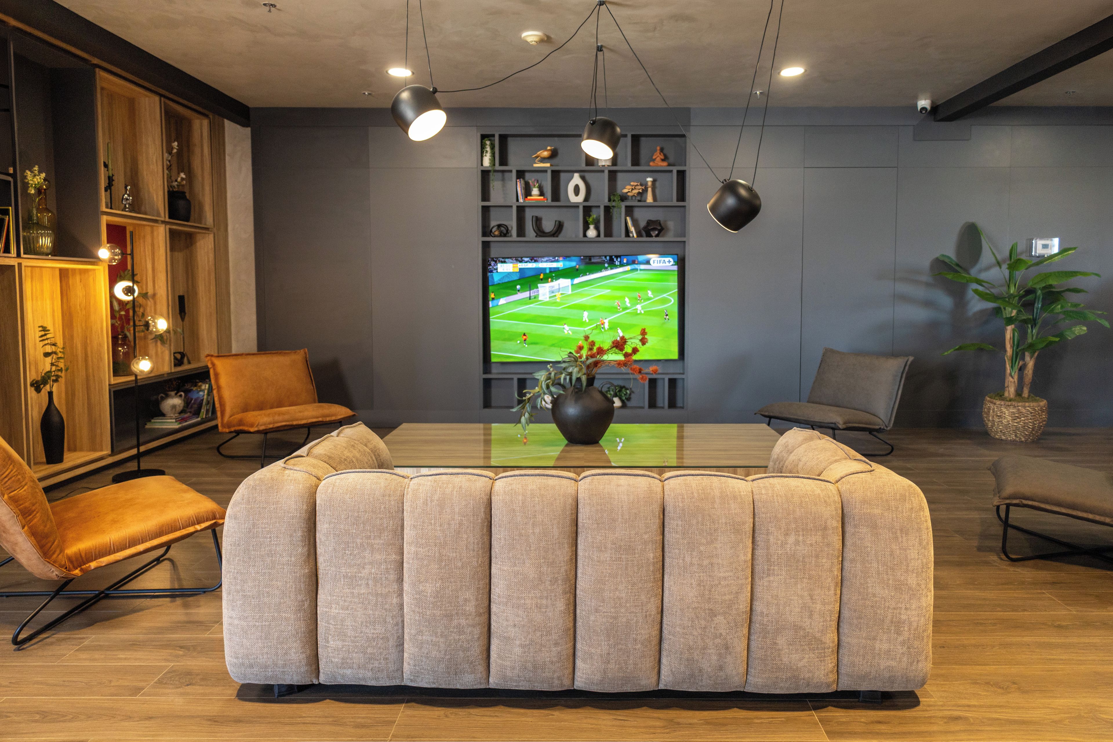 Una sala de estar moderna con un sofá modular, un televisor de pantalla plana y una estantería.