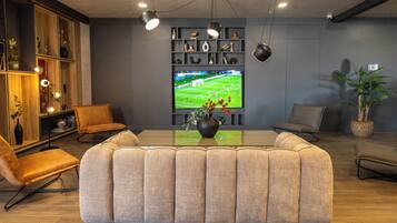 Una sala de estar moderna con un sofá modular, un televisor de pantalla plana y una estantería.