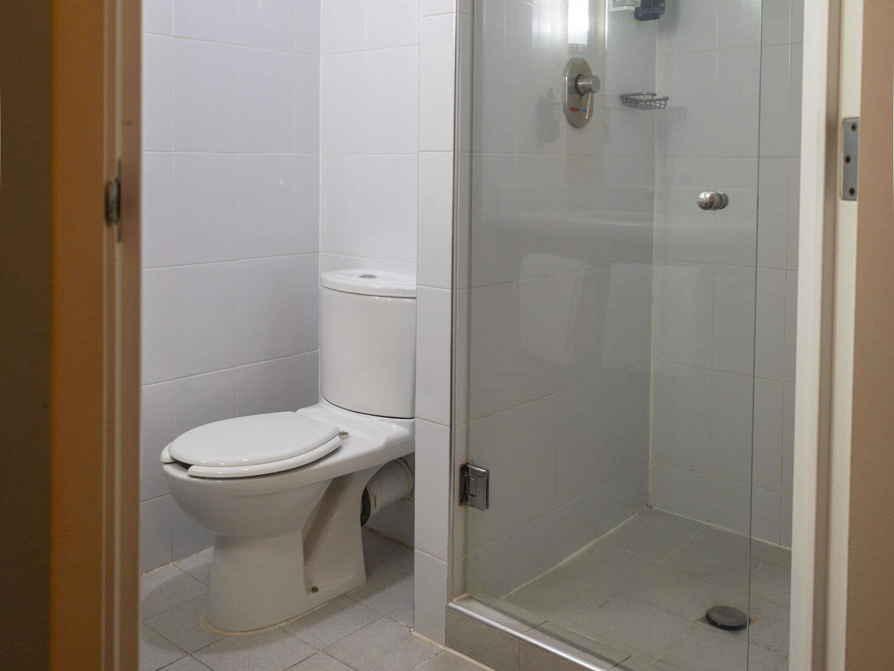 A bathroom with a toilet, a glass shower enclosure, and a tiled floor.